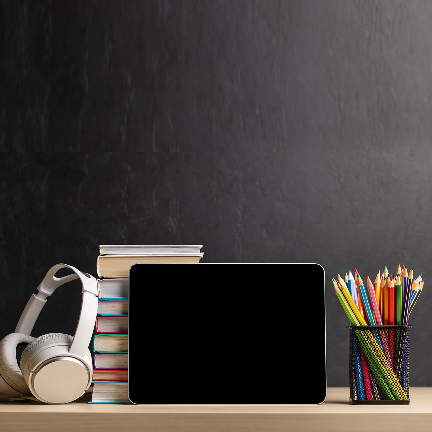 Tablet with colorful pencils and stack of books